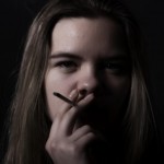Teen girl smoking with black background: Smokedistrict Cannabis blog
